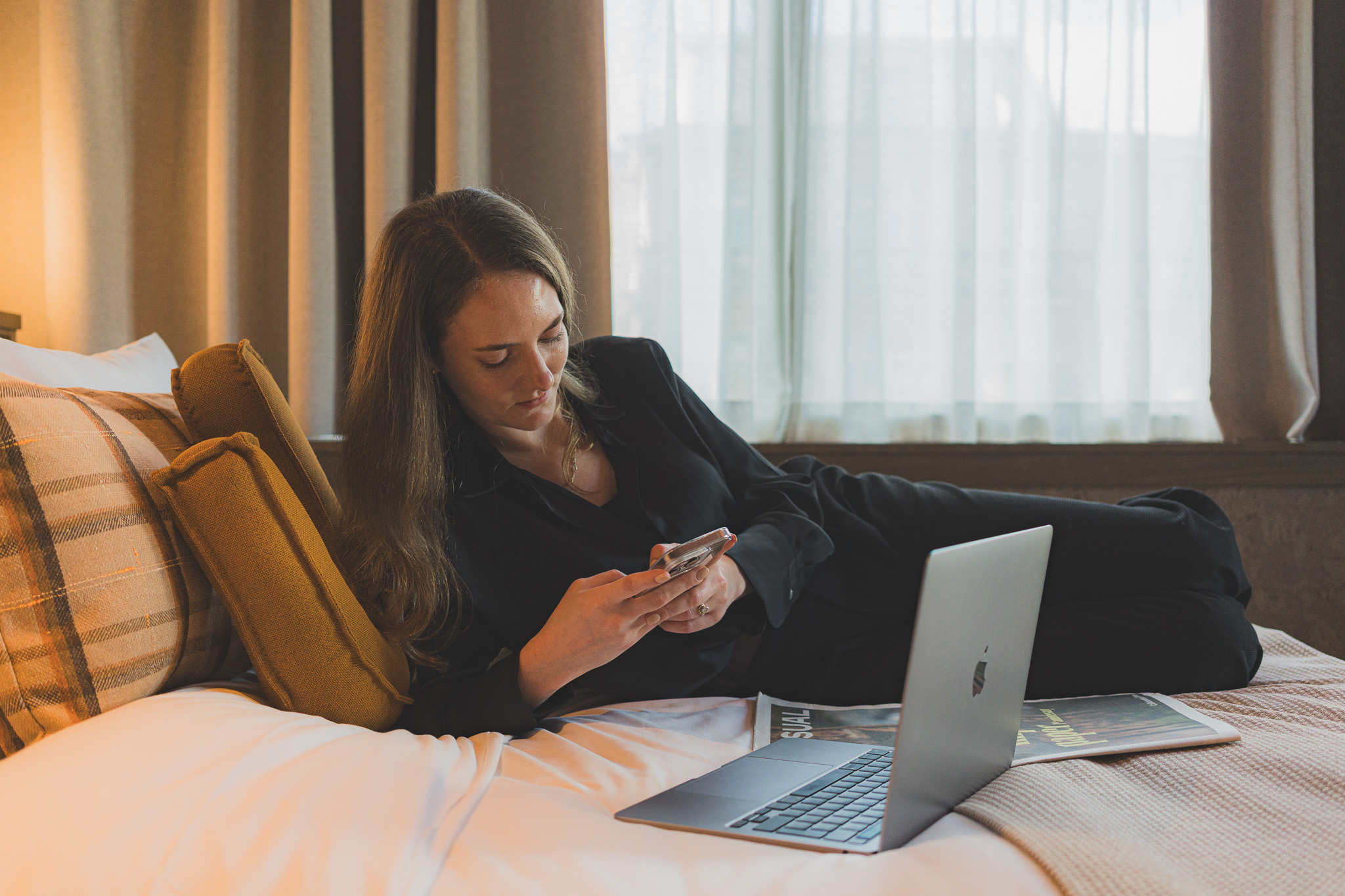 Girl on the bed with laptop and phone 4-star design hotel The Usual Brussels